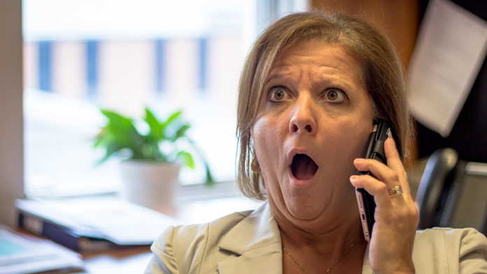 Femme surprise en parlant au téléphone.