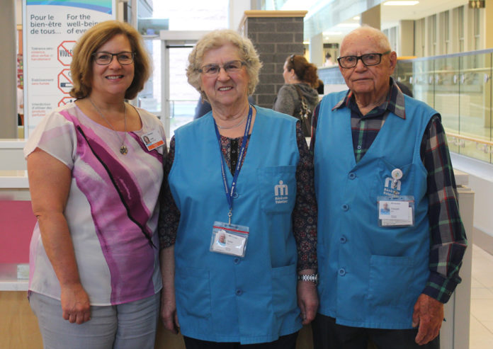 Trois adultes dans l'entrée principale de l'hôpital qui sourient