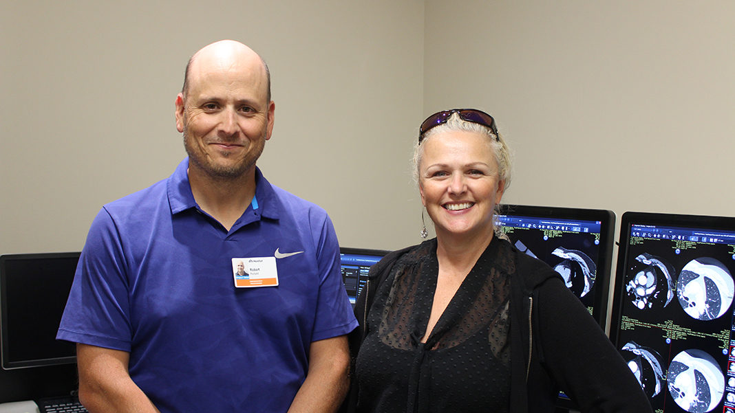 Deux professionnels devant des écrans où l'on voit des images d'examens d'imagerie médicale.