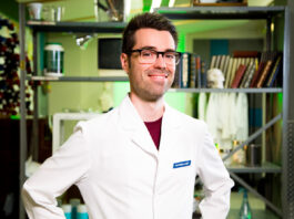 Homme en sarrau blanc souriant mains sur les hanches