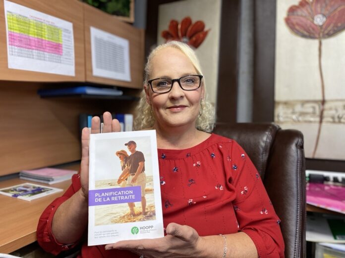 Femme blonde avec chandail rouge qui tient un pamphlet sur la retraite