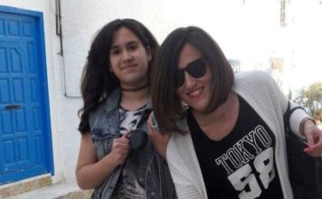 Mère et sa fille souriante devant une porte bleue