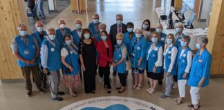 Groupe de personnes portant chacun une veste bleue, entourant un collant géant sur le sol à l'effigie d'un papillon