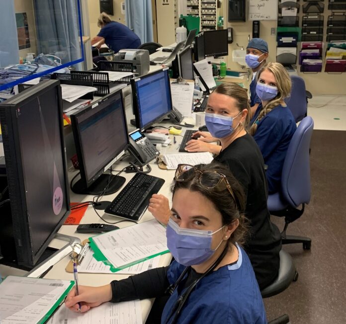 Quelques travailleurs de la santé, masqués, travaillant à l'ordinateur