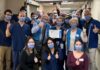 Groupe de membres du personnel hospitalier dans un corridor. Ils sont souriants malgré le port du masque et font tous le signe du pouce en l'air. la personne au milieu de l'image tient un certificat dans ses mains