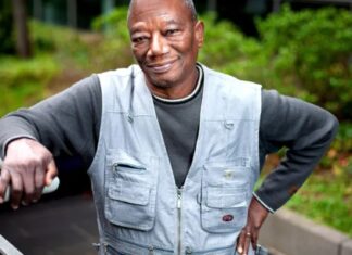 Grégoire Ahongbonon, vêtu d'une veste de jeans, appuyé contre la rampe d'un escalier extérieur