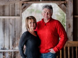 Photo d'une femme et d'un homme cinquantenaires souriants, dans une grange