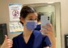 Jeune femme masquée et portant des "scrubs" qui prend un selfie dans une salle de bain de Montfort avant son premier quart de travail