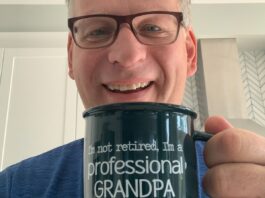 Philippe Marleau souriant, tenant bien en évidence une tasse où il est écrit (en anglais) qu'il n'est pas retraité mais un grand-père à plein temps.