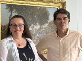 Une femme et un homme sourient devant un tableau