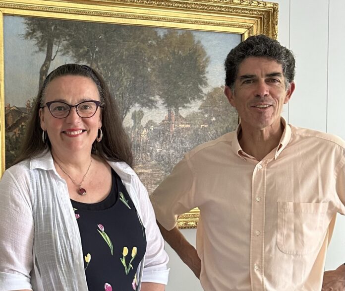 Une femme et un homme sourient devant un tableau