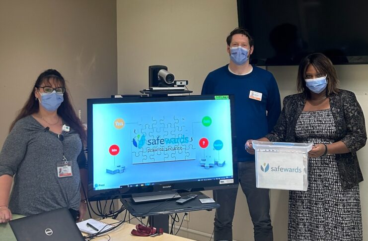 Deux femmes et un homme avec un certificat et un écran de télévision
