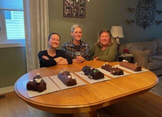 Trois femmes devant cinq bûches de Noël sur une table de cuisine