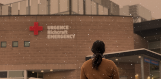 Femme en chandail brun devant une urgence avec de la neige